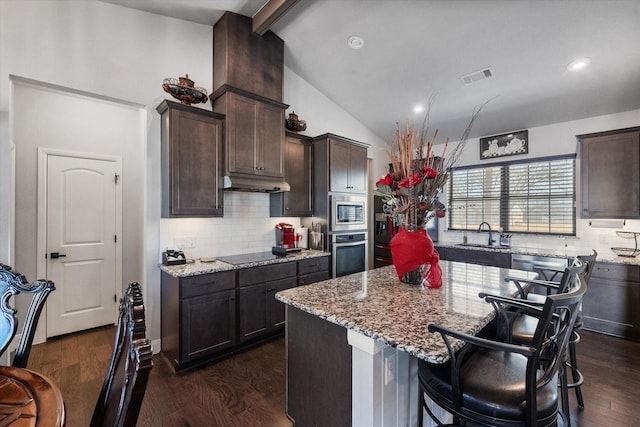 kitchen featuring a center island, vaulted ceiling with beams, stainless steel appliances, visible vents, and under cabinet range hood