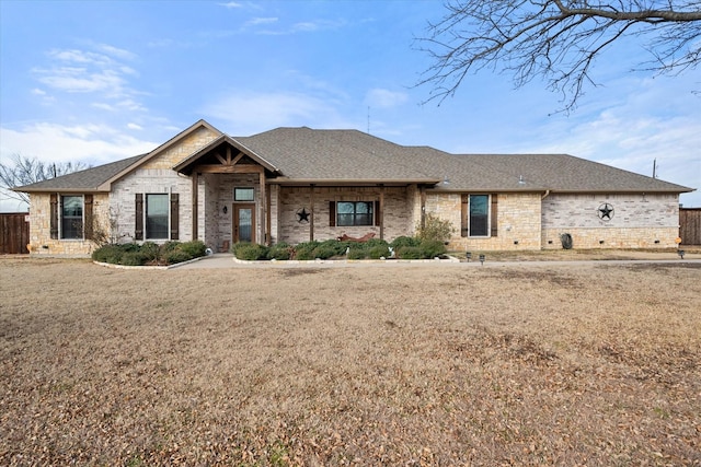 view of front facade with a front yard, roof with shingles, and brick siding