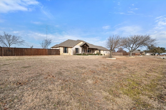 exterior space featuring a yard, stone siding, and fence