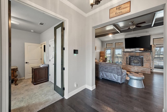 interior space with a fireplace, wood finished floors, a ceiling fan, visible vents, and baseboards