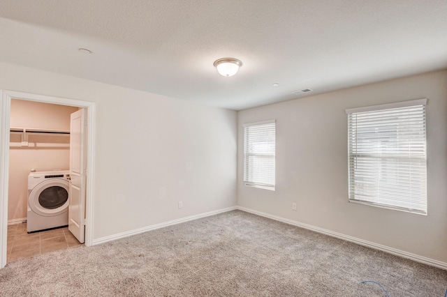 unfurnished bedroom with light colored carpet, a spacious closet, washer / clothes dryer, and a closet