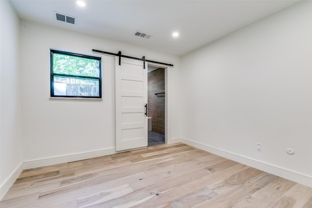 spare room featuring light wood-type flooring and a barn door