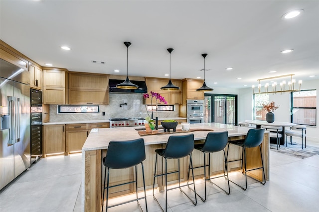 kitchen with a large island, custom exhaust hood, appliances with stainless steel finishes, decorative light fixtures, and tasteful backsplash