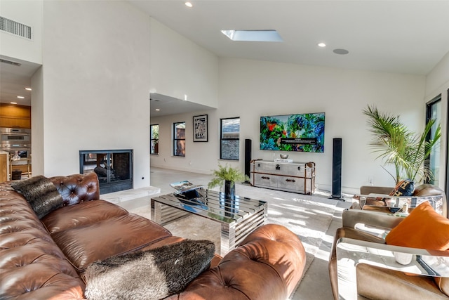 living room featuring a towering ceiling and a skylight