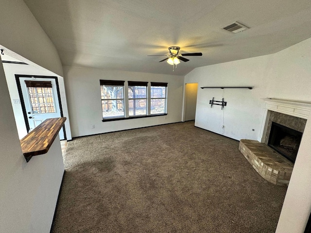 unfurnished living room featuring ceiling fan, a brick fireplace, a textured ceiling, and dark carpet