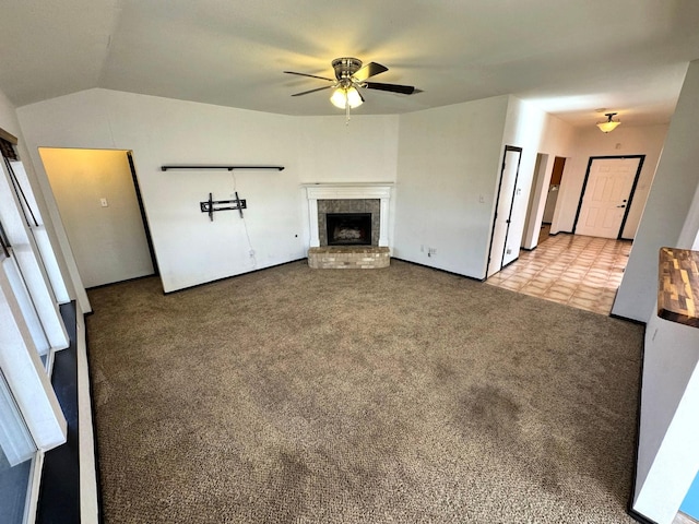 unfurnished living room with ceiling fan, light colored carpet, a brick fireplace, and vaulted ceiling