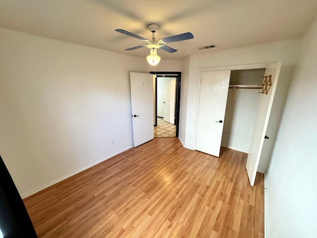 unfurnished bedroom featuring light wood-type flooring, ceiling fan, and a closet