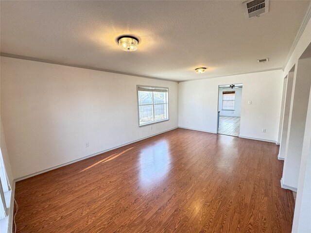 spare room with crown molding and wood-type flooring