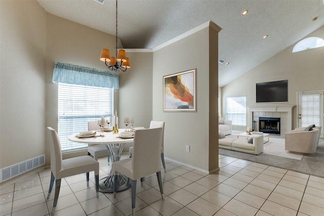 dining space with a wealth of natural light, a tiled fireplace, a textured ceiling, and light tile patterned floors