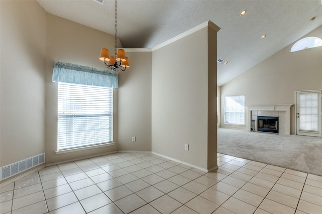 spare room with light tile patterned flooring, an inviting chandelier, high vaulted ceiling, a textured ceiling, and a fireplace