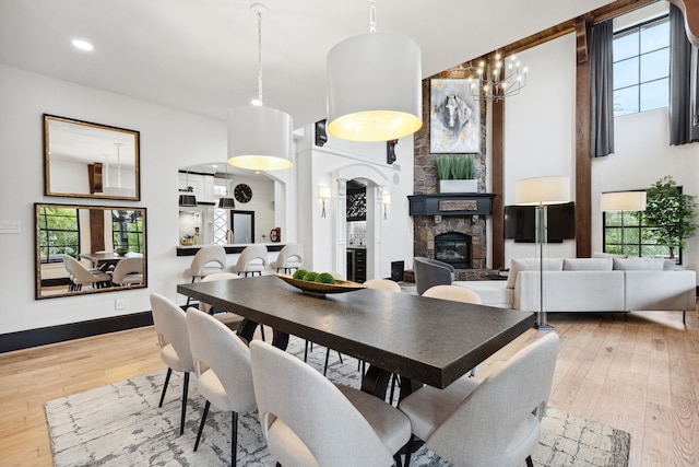 dining room featuring a fireplace, a notable chandelier, and light hardwood / wood-style floors