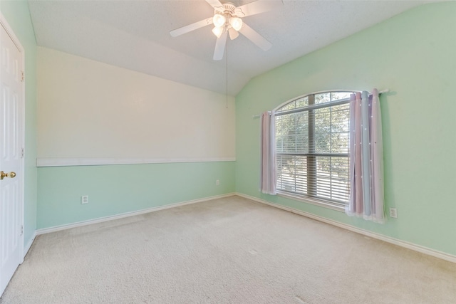 carpeted empty room with ceiling fan and vaulted ceiling