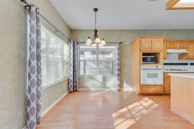 kitchen with white appliances, light hardwood / wood-style flooring, a notable chandelier, decorative light fixtures, and light brown cabinets