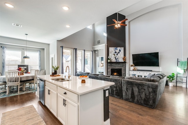 kitchen featuring a center island with sink, a fireplace, sink, white cabinetry, and stainless steel dishwasher