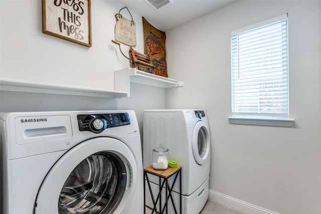 laundry room with light tile patterned flooring, washing machine and dryer, and a wealth of natural light