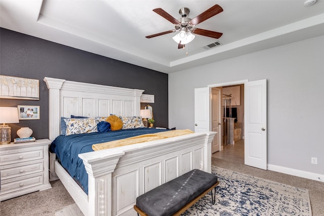 bedroom featuring ceiling fan, light colored carpet, and a raised ceiling