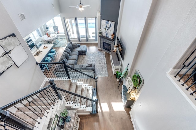 staircase with ceiling fan, hardwood / wood-style floors, and a high ceiling