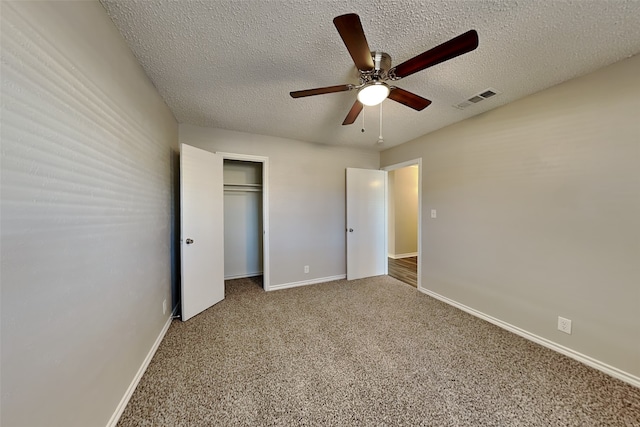 unfurnished bedroom with a closet, a textured ceiling, ceiling fan, and carpet flooring