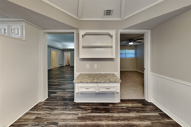 interior space featuring a textured ceiling, ornamental molding, and dark hardwood / wood-style floors