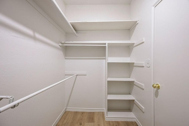 walk in closet with light hardwood / wood-style floors