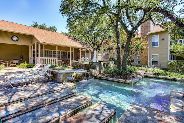 view of pool featuring a hot tub, a patio, and pool water feature