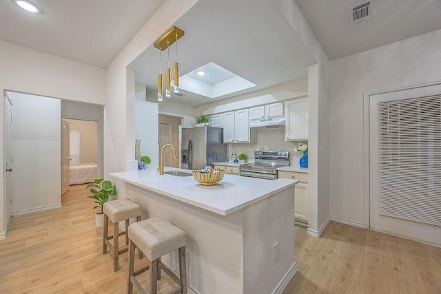 kitchen featuring pendant lighting, sink, stainless steel appliances, a kitchen breakfast bar, and white cabinets