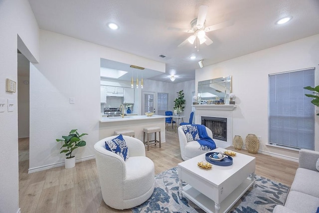 living room with ceiling fan, sink, and light hardwood / wood-style floors