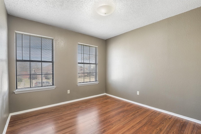 empty room featuring a textured ceiling and dark hardwood / wood-style flooring