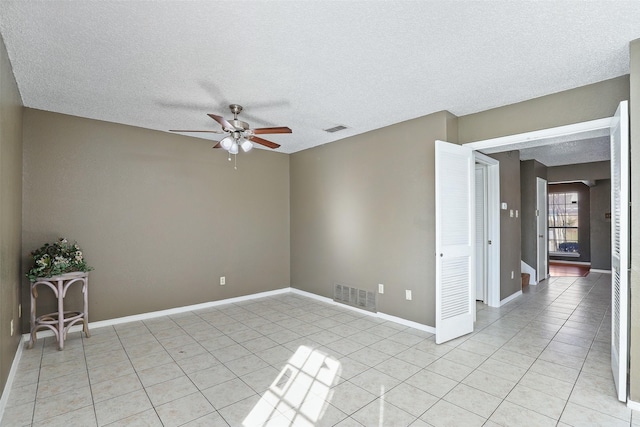 spare room featuring a textured ceiling, ceiling fan, and light tile patterned flooring