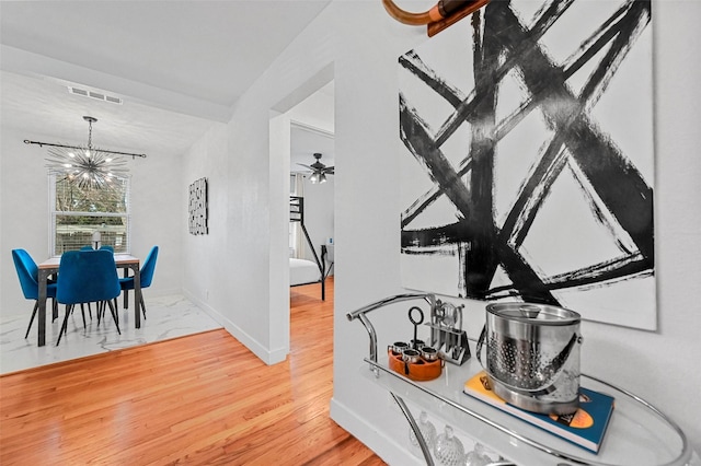 interior space with ceiling fan with notable chandelier and wood-type flooring