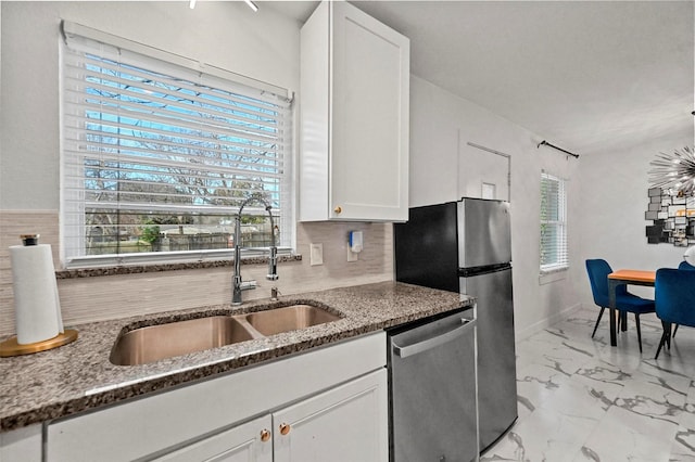 kitchen with appliances with stainless steel finishes, white cabinets, dark stone countertops, and sink