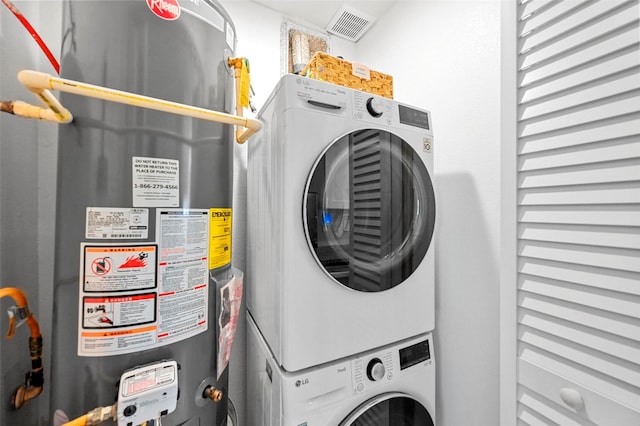 washroom featuring stacked washer / drying machine and gas water heater