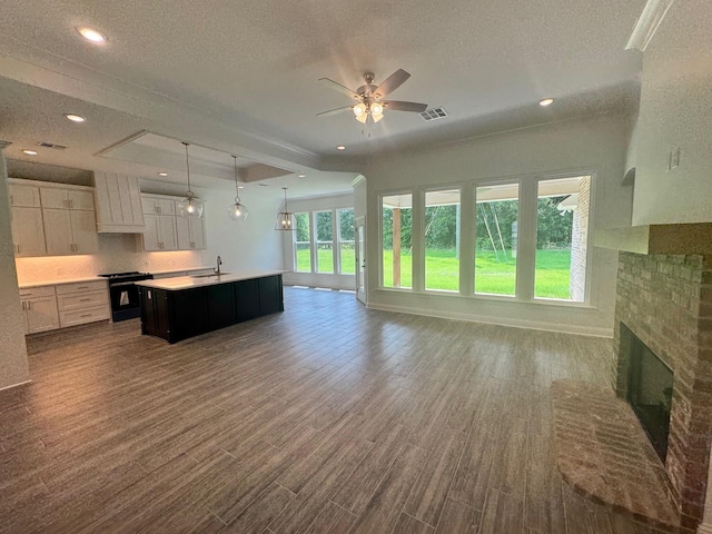 686 Newburyport St, Blanchard, LA 71107 - unfurnished living room with ceiling fan, a brick fireplace, dark wood-style flooring, a textured ceiling, and a sink