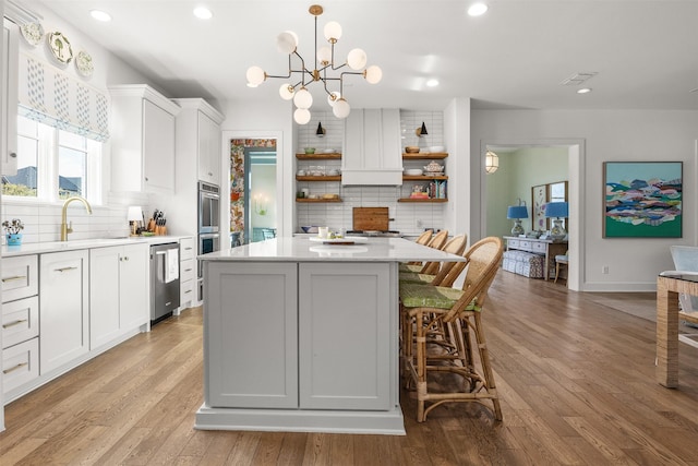 kitchen featuring white cabinets, a kitchen island, stainless steel appliances, and decorative light fixtures