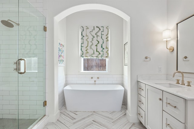 bathroom featuring separate shower and tub, tile walls, and vanity