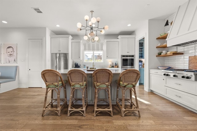 kitchen with decorative backsplash, white cabinetry, stainless steel appliances, and a breakfast bar area