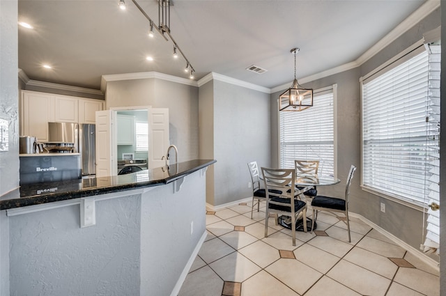 kitchen with washer / dryer, white cabinetry, hanging light fixtures, stainless steel fridge, and ornamental molding