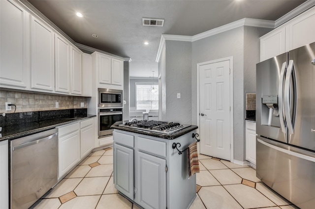 kitchen featuring crown molding, white cabinets, stainless steel appliances, and dark stone countertops