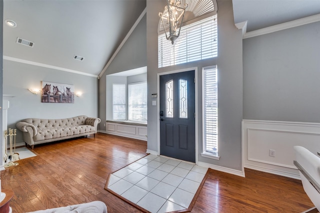 foyer entrance featuring high vaulted ceiling, crown molding, and hardwood / wood-style floors