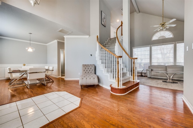 foyer entrance featuring ceiling fan, high vaulted ceiling, ornamental molding, and light hardwood / wood-style flooring