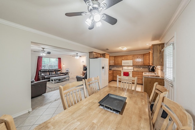 dining room with light tile patterned flooring, crown molding, and sink