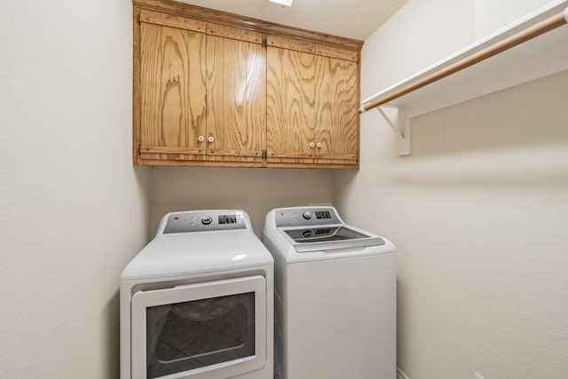 laundry room with independent washer and dryer and cabinets