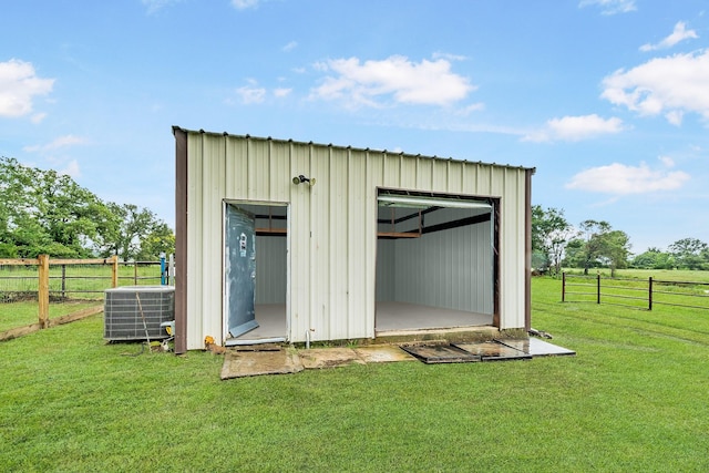 view of outdoor structure featuring a lawn, central AC, and a rural view