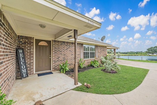 view of exterior entry with a yard and a water view