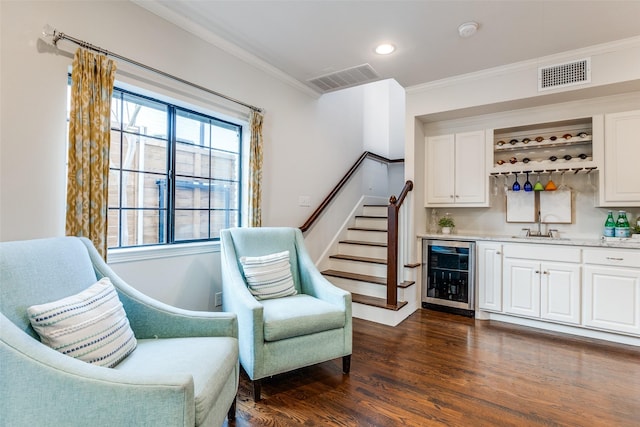 bar with wine cooler, ornamental molding, dark wood-type flooring, white cabinets, and sink