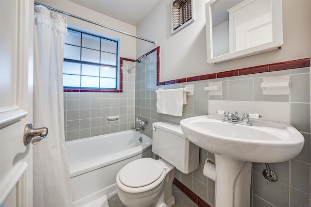 bathroom with tile walls, tile patterned flooring, shower / tub combo with curtain, and toilet