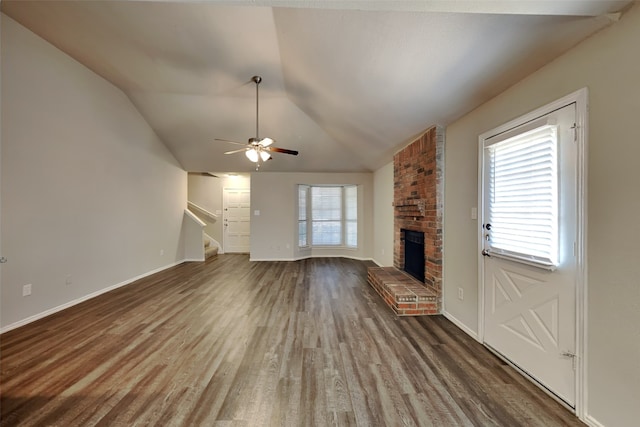 unfurnished living room with lofted ceiling, a brick fireplace, ceiling fan, and dark wood-type flooring