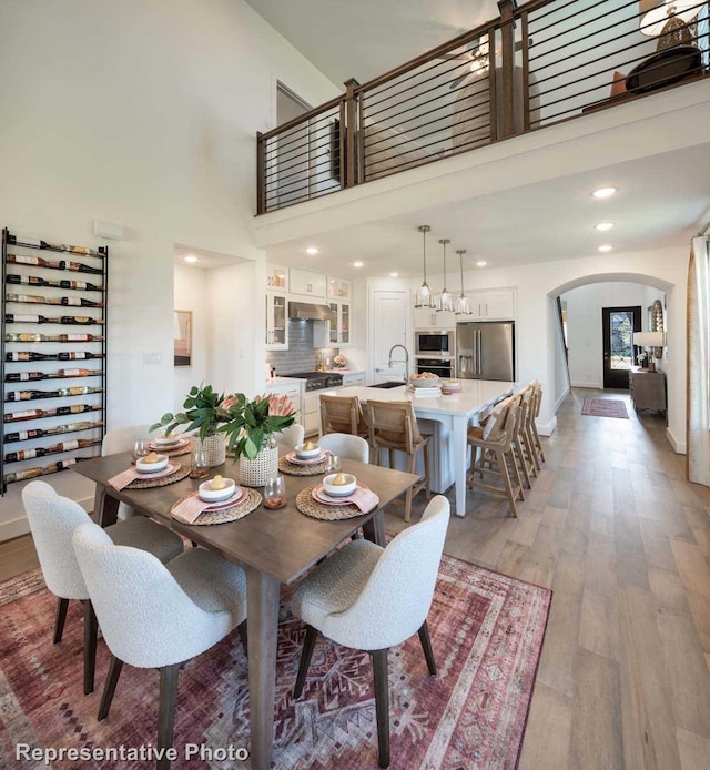 dining room with sink, light wood-type flooring, and a towering ceiling