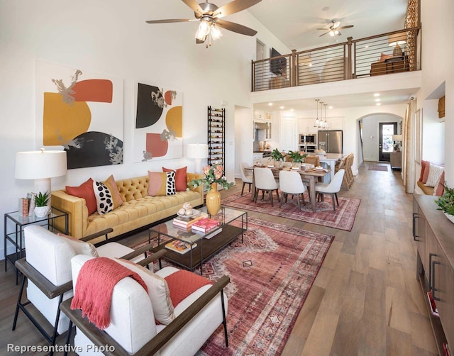 living room featuring a towering ceiling, ceiling fan, and dark hardwood / wood-style flooring