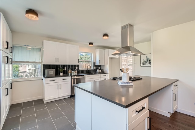 kitchen featuring stainless steel appliances, white cabinets, island range hood, and decorative backsplash